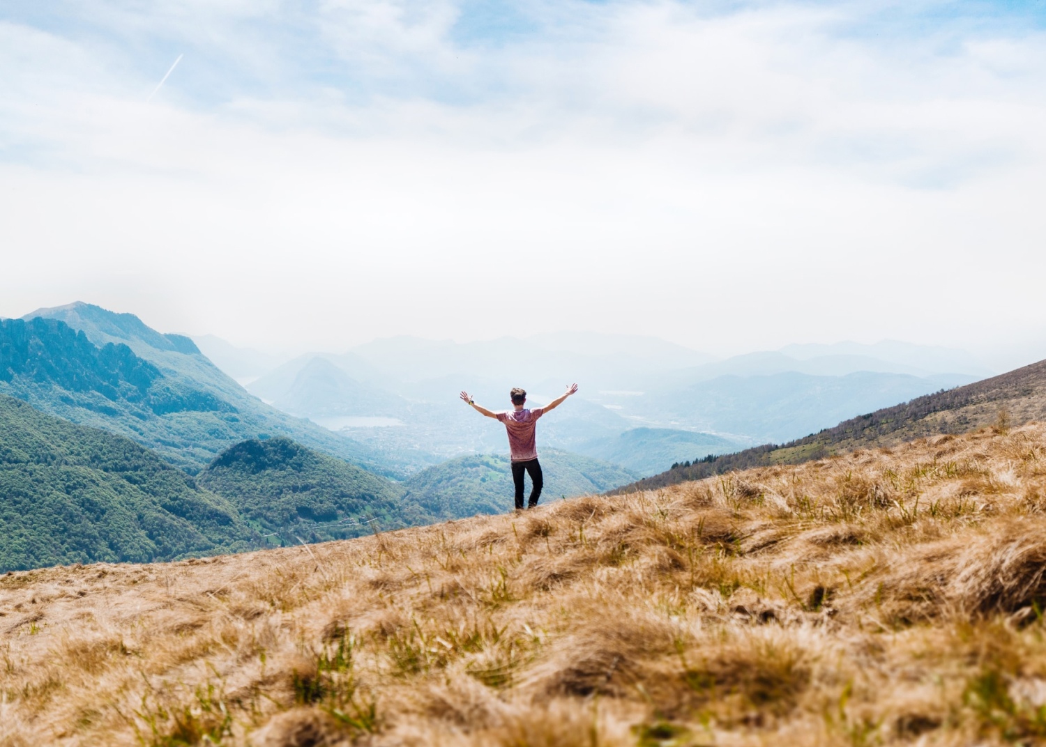 Person celebrating with arms raised on a mountain top